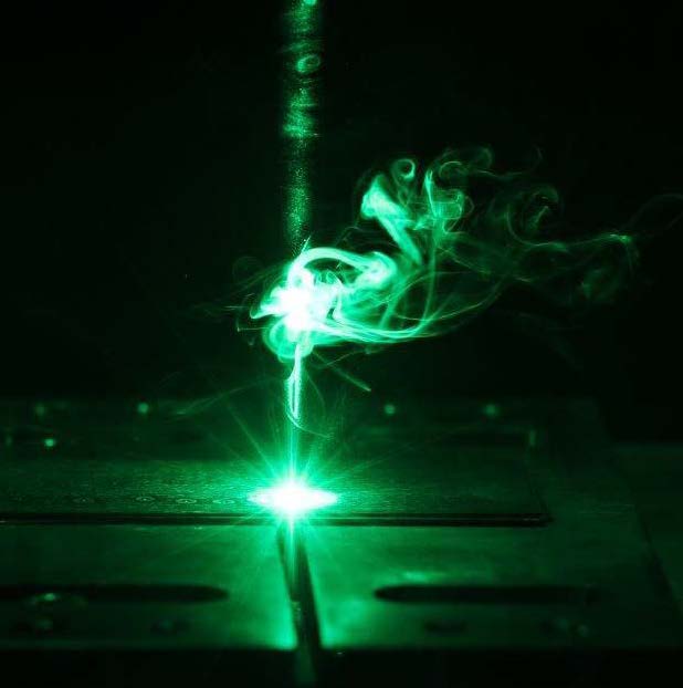 Materialbearbeitung mit einem grünen Laserstrahl.